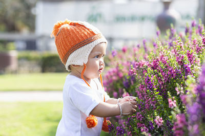 Girl wearing hat standing against purple flowering plants