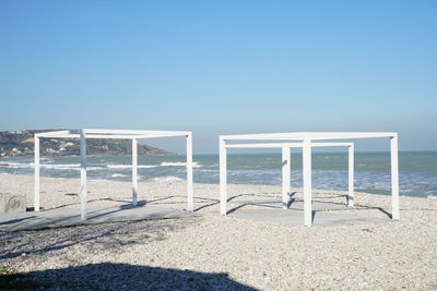 Lifeguard hut on beach against clear blue sky