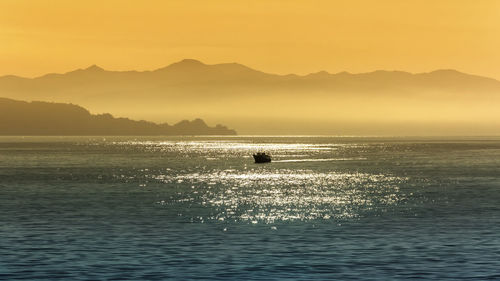 Silhouette people on sea against sky during sunset