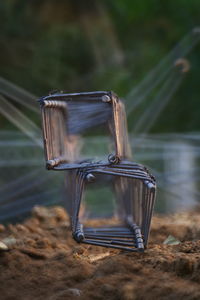 Close-up of metallic chair on field by lake