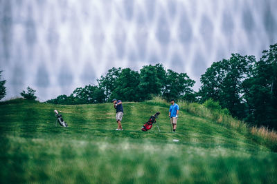 People playing on field against trees