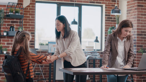 Mother holding daughters hand in office