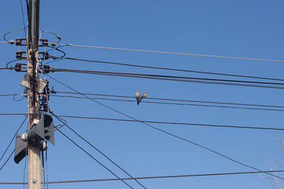 Low angle view of power lines against clear blue sky