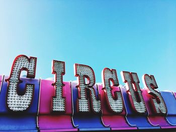 Low angle view of text on building against clear blue sky