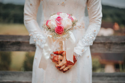 Midsection of bride holding bouquet during wedding