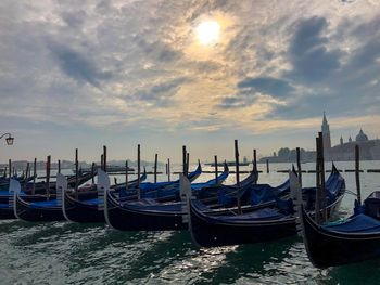 Boats moored in canal against cloudy sky