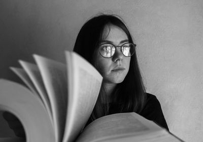 Thoughtful young woman by book looking away