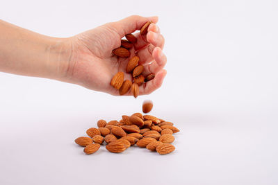 Cropped hand of person holding pills over white background