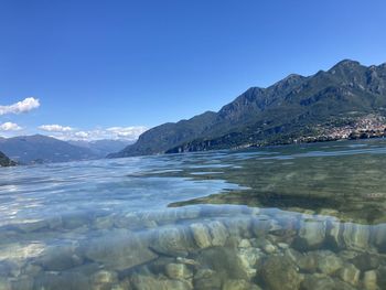 Scenic view of sea and mountains against clear blue sky