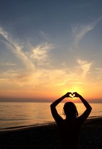 Silhouette woman making heart shape from hands