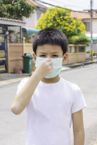 Portrait of boy wearing mask standing on road