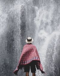 Rear view of man with scarf against waterfall