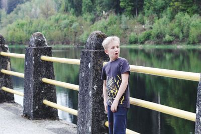 Boy standing on railing against trees