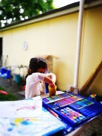 Tilt-shit image of girl putting hands in glass by palette on table