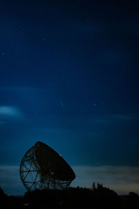 Low angle view of electricity pylon against sky at night