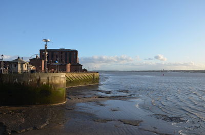 Buildings by sea against clear blue sky