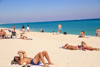 People at beach against clear sky