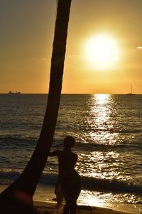 Silhouette people on beach against sky during sunset