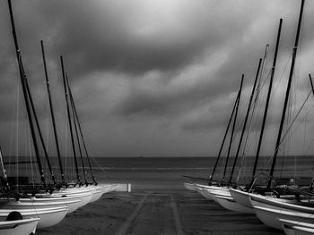 Sailboats moored at harbor against sky