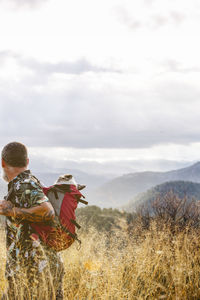 Rear profile view of man with dog in backpack on mountain person