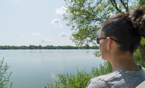 Rear view of woman wearing sunglasses against lake