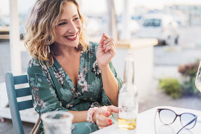 Happy woman having beer while sitting at outdoor restaurant