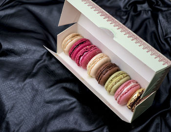 High angle view of macaroons in box on black fabric