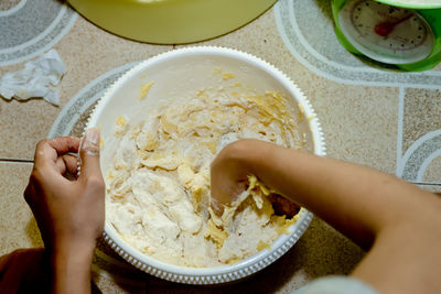 Midsection of woman preparing food in bowl on table