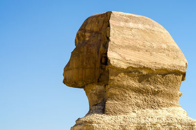 Low angle view of rock formation against clear blue sky