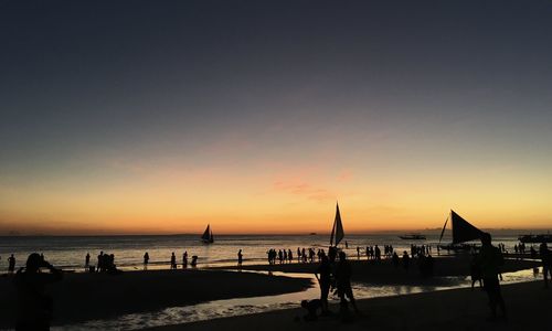 Silhouette people on beach against sky during sunset