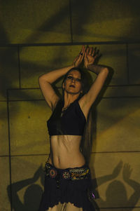 Young woman standing against wall