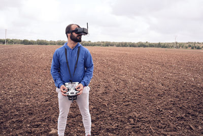 Young man flies drone with glasses in the field