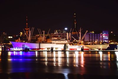 Illuminated pier over river against sky at night