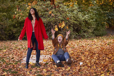 Friends playing with autumn leaves in park