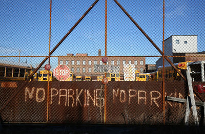 Buses parked at parking lot seen through fence