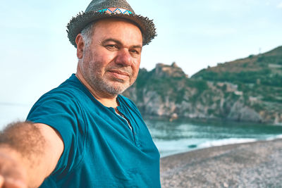 Happy, smiling mature bearded man taking a selfie on seaside background. summertime on beach