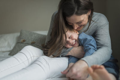 Happy mother playing with son on bedroom at home