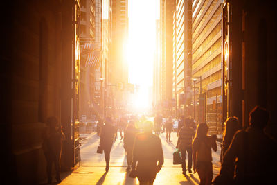 People on street amidst buildings in city during sunset
