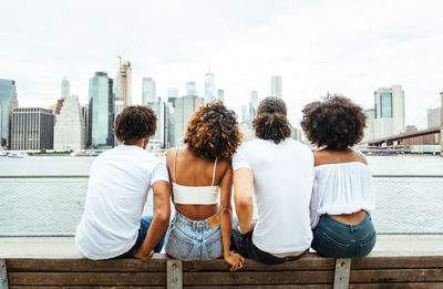 Rear view of people sitting in city against sky