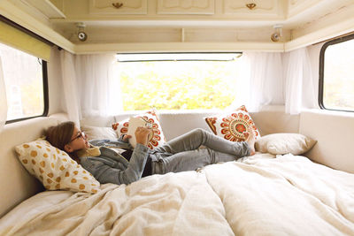 Girl using digital tablet lying on bed in motor home