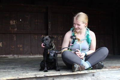 Woman sitting with puppy against wall