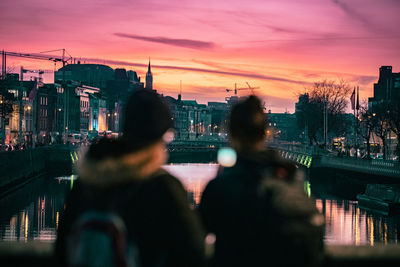 Rear view of people in city against sky during sunset