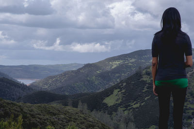 Rear view of woman standing on mountain against sky