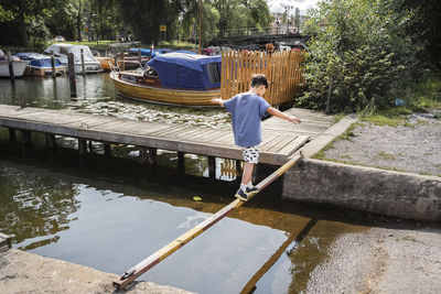 Boy balancing on narrow metal bar over water