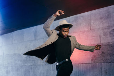 Young man wearing hat standing against wall