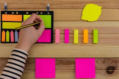 Cropped hand of person writing on colorful adhesive notes