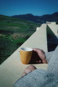 Hand holding coffee cup against mountain