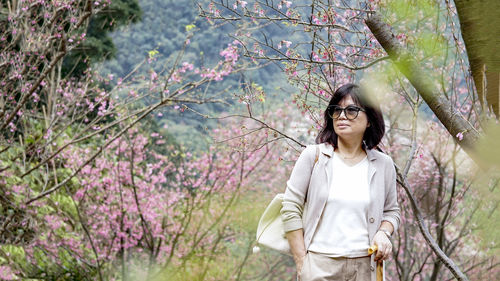 Young woman standing by cherry blossom