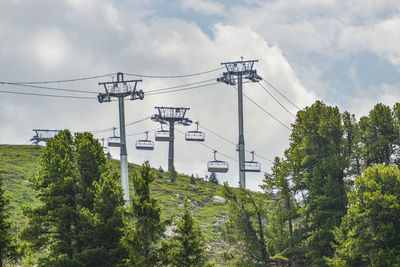 Low angle view of trees against sky and chair lift