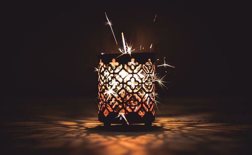 Close-up of illuminated sparkler in patterned container at night